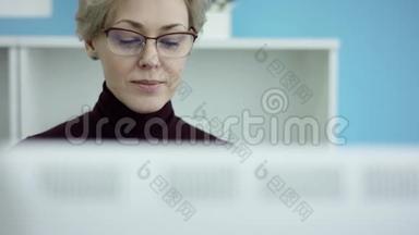 年轻的休闲女士坐在<strong>办公</strong>桌前，用笔记本电脑，<strong>接电话</strong>，打<strong>电话</strong>，微笑着在手机上说话